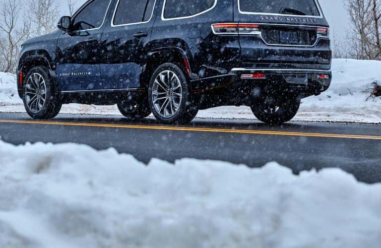 2023 Grand Wagoneer Rear Driver Side View Driving on Road in Snow
