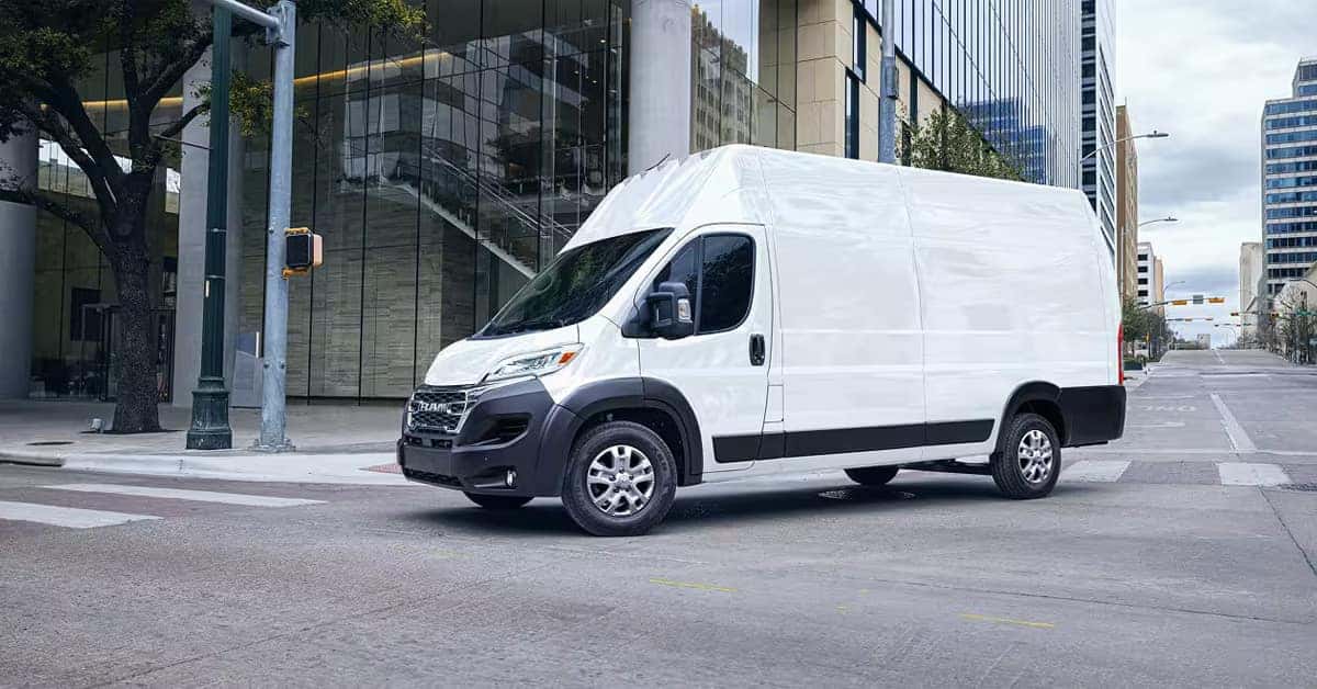A white high-roof Ram ProMaster cargo van parked on a city street.
