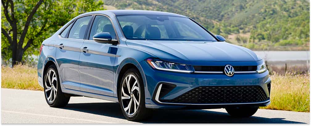 Front three-quarter view of a blue 2026 Volkswagen Jetta sedan parked on a paved road.