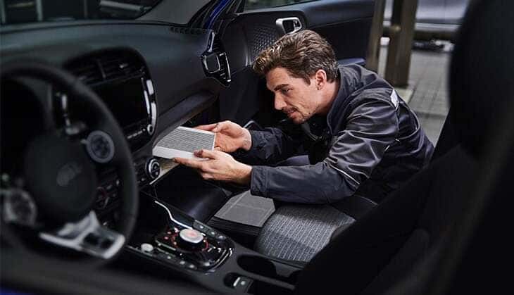 A Kia technician installing a new cabin air filter