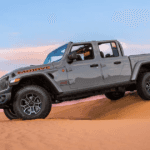 A silver 2025 Jeep Gladiator driving in the desert