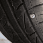 A nail in the right side of a tire with the sun shining upon it