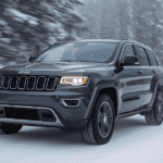 A 2025 Jeep Cherokee driving quickly down the snowy road