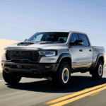 a 2026 Ram 1500 RHO driving fast on a road with a beach dune in the background