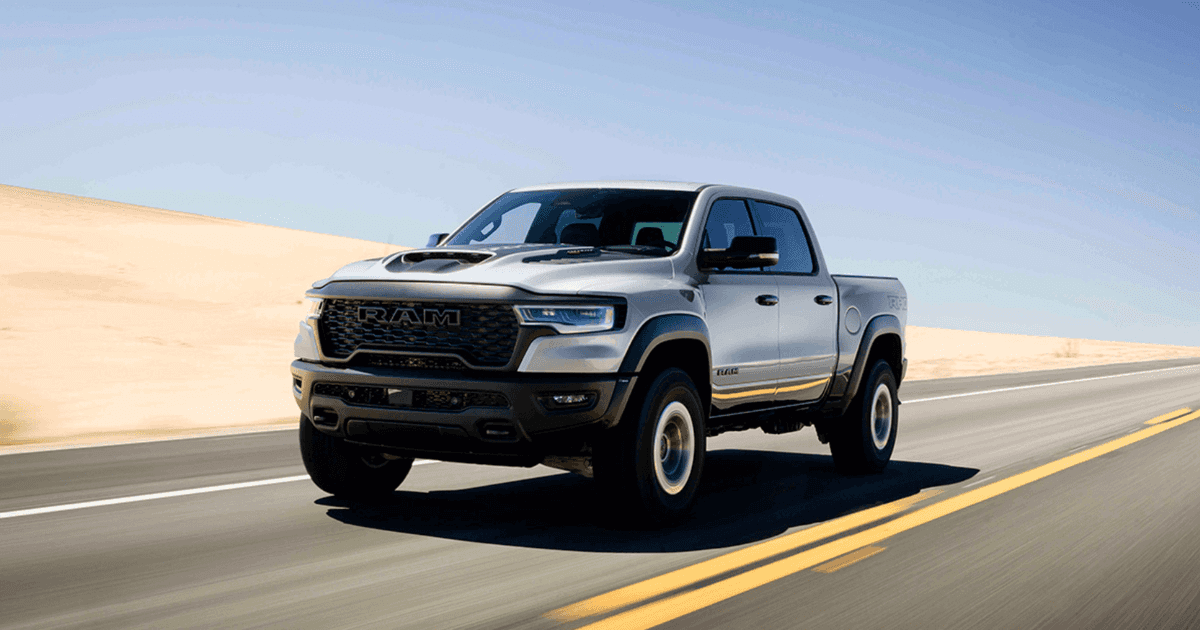 a 2026 Ram 1500 RHO driving fast on a road with a beach dune in the background