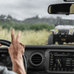 A man driving a jeep waving to a jeep owner